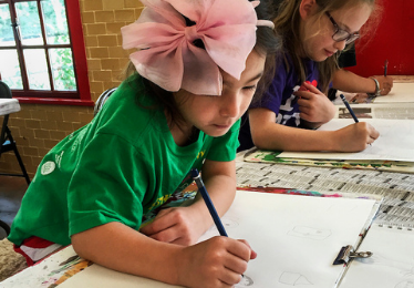 girl with large hair bow drawing in art class