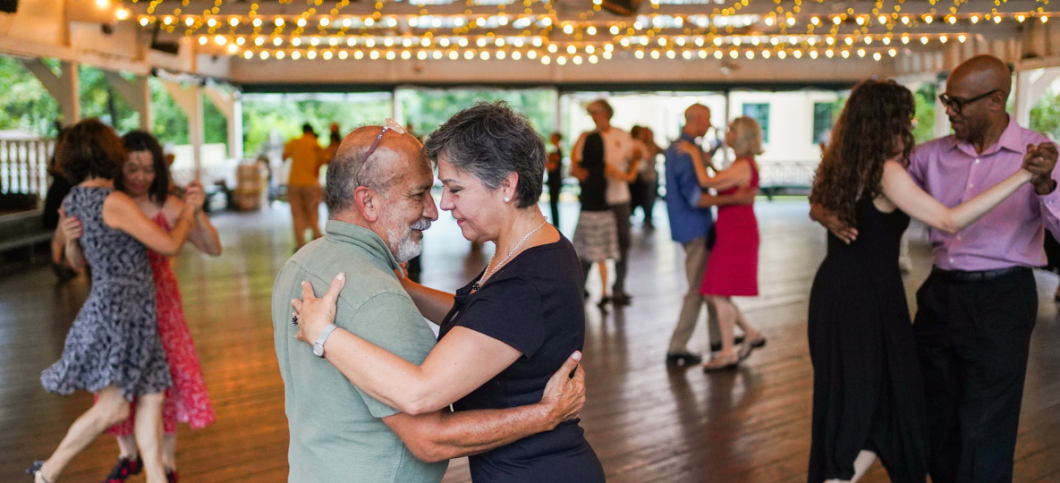 A couple dances in a pavilion with twinkling lights