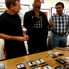 Three people look at photograph prints on a table
